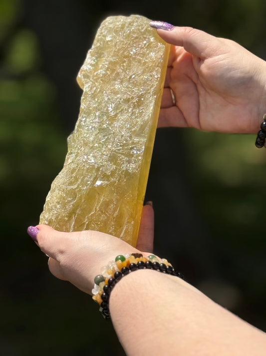 Angled view of a citrine crystal slab highlighting its raw textured edge and glossy polished surface with golden translucence.