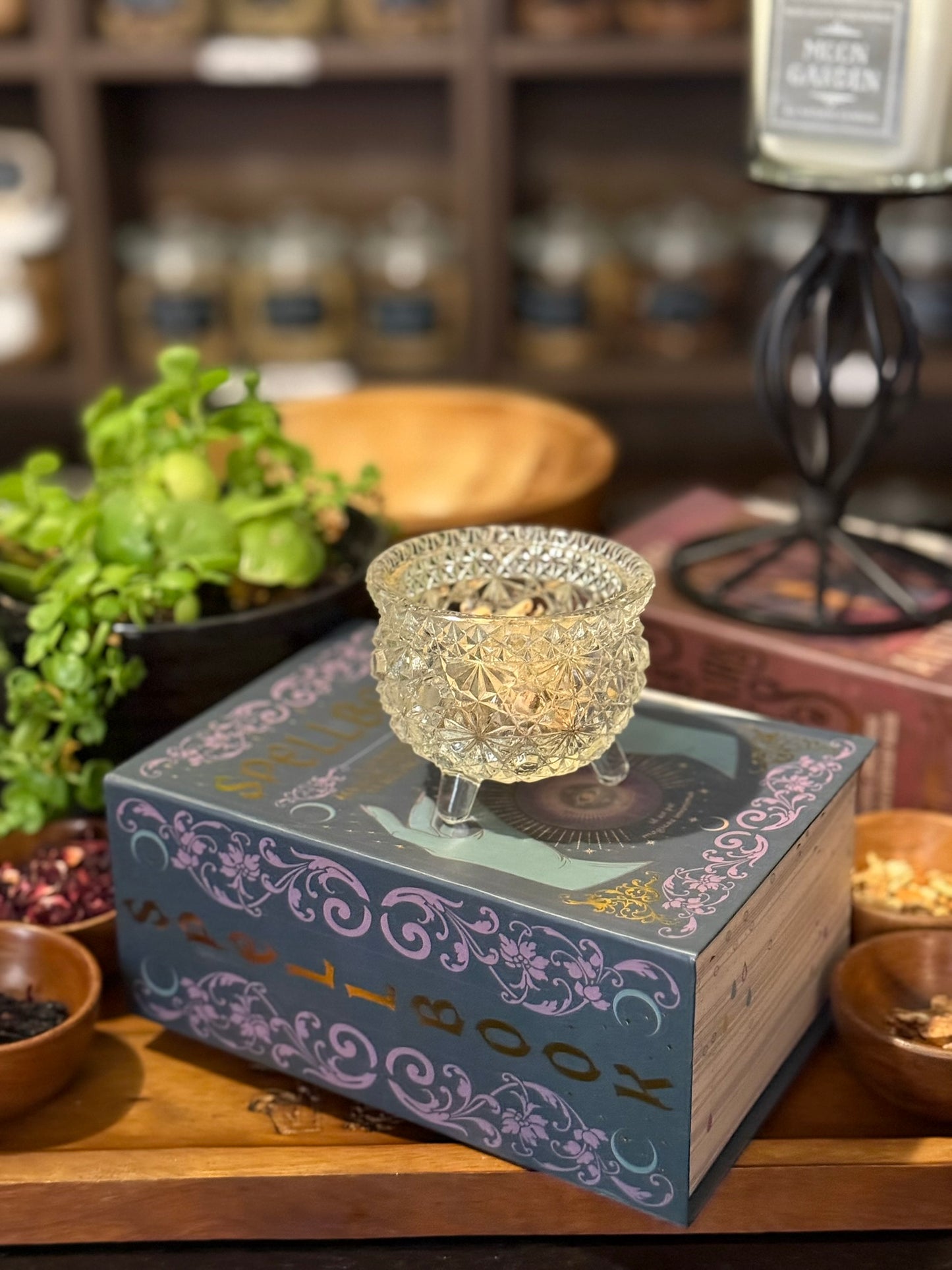 Handcrafted citrus herbal tea in a vintage crystal chalice, featured on an ornate spellbook display at Dear Universe Apothecary, surrounded by natural botanicals and witchy apothecary decor