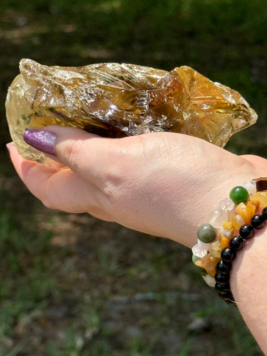 Angled image of a smoky citrine free-form with visible raw textures and polished edges, reflecting golden-brown light in an outdoor setting