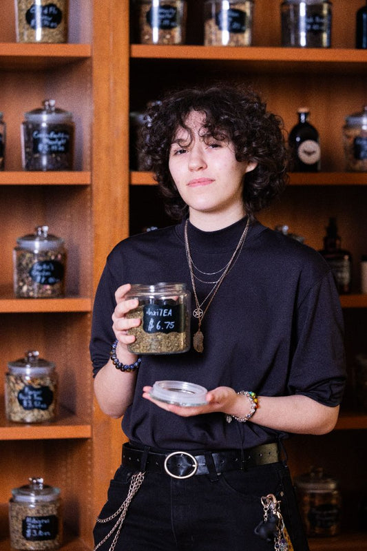 A young lady holding a glass jar of tea with teas in the background