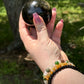 Golden Obsidian sphere held in hand outdoors, showcasing its polished surface with subtle golden sheen—used for grounding, protection, and energy work.