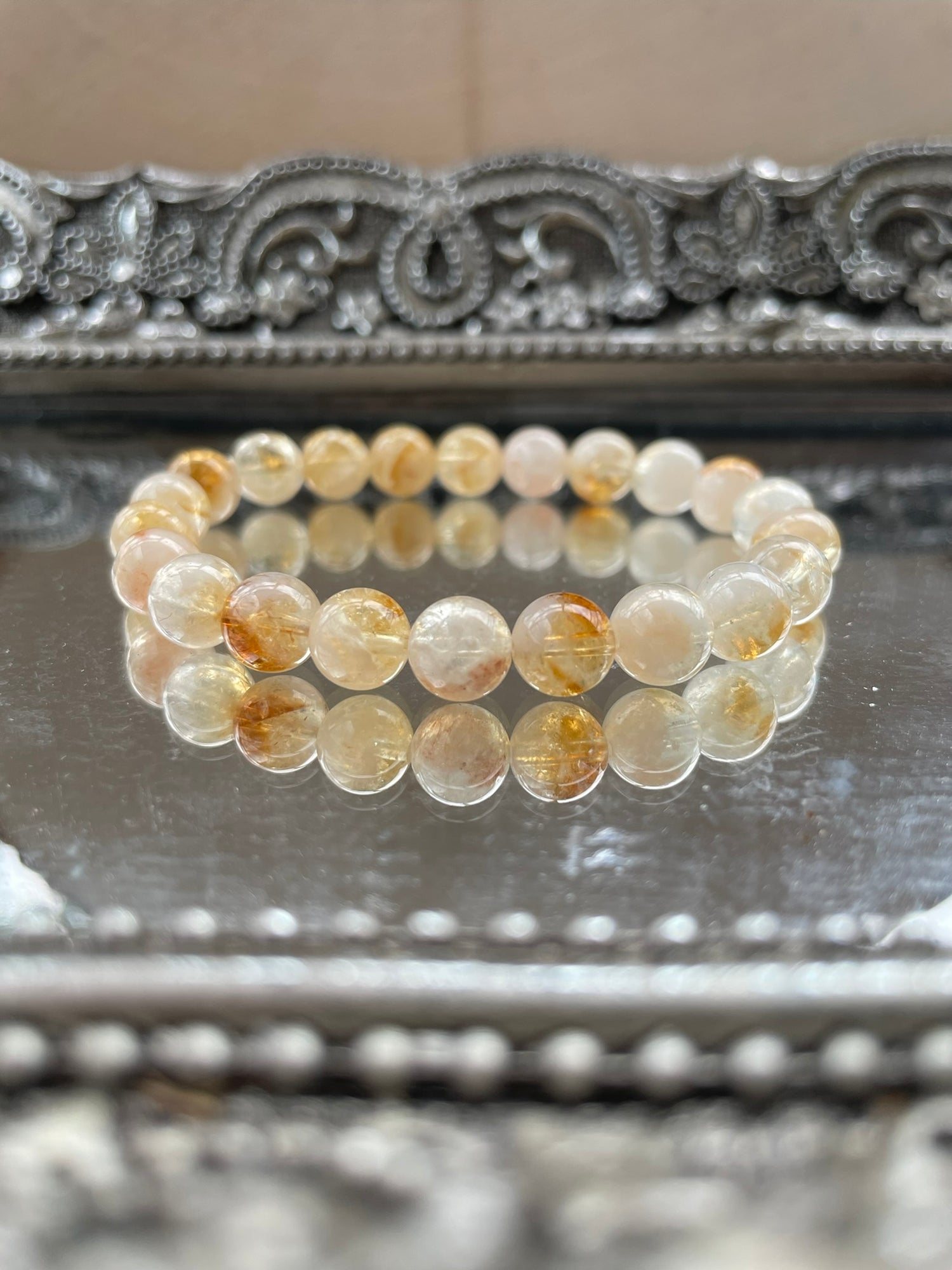 Handmade citrine bracelet with natural golden-yellow beads displayed on a reflective surface, symbolizing abundance, confidence, and chakra healing