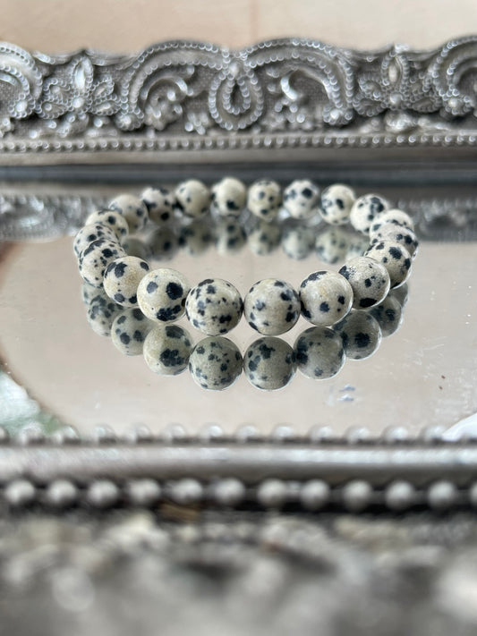 Handmade Dalmatian Jasper bracelet featuring natural spotted beads displayed on a mirrored silver tray, symbolizing grounding and joyful energy for chakra healing