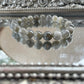 Handmade Labradorite bracelet with reflective gray and blue flash beads displayed on a silver mirrored surface, ideal for intuition and energy protection
