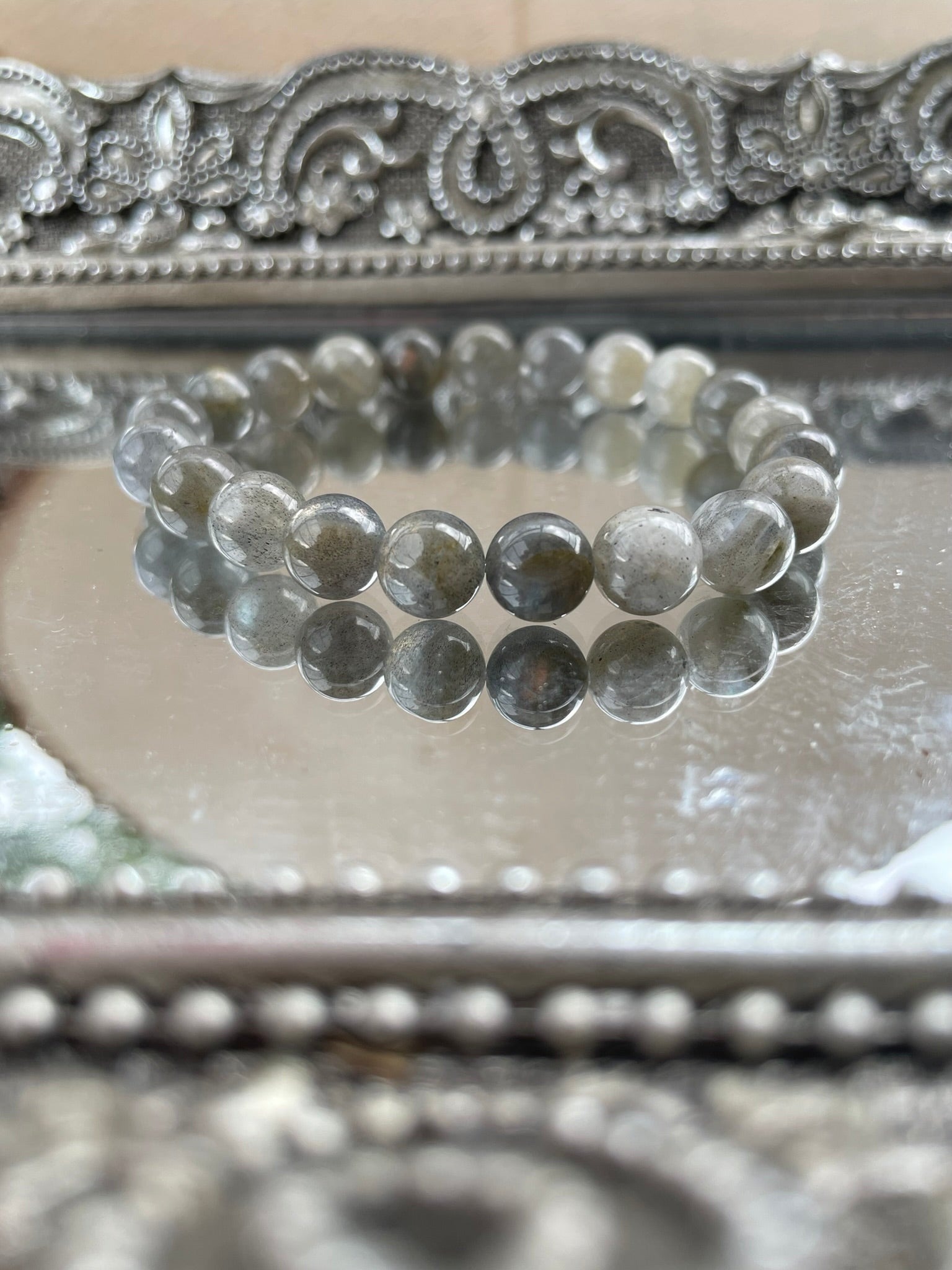 Handmade Labradorite bracelet with reflective gray and blue flash beads displayed on a silver mirrored surface, ideal for intuition and energy protection