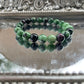Handmade Ruby in Zoisite bracelet featuring green and deep pink gemstone beads displayed on a silver reflective surface, ideal for heart chakra and emotional healing