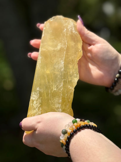 Front view of a natural citrine slab held in hand, showing golden-yellow clarity and polished finish under daylight.