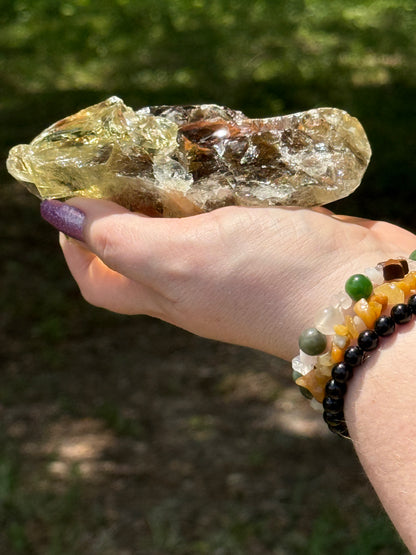 Raw-style smoky citrine crystal showing its deep amber core and layered structure, captured in bright daylight to highlight its sparkle and depth.