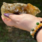 Angled image of a smoky citrine free-form with visible raw textures and polished edges, reflecting golden-brown light in an outdoor setting
