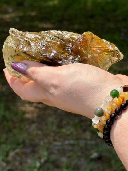 Angled image of a smoky citrine free-form with visible raw textures and polished edges, reflecting golden-brown light in an outdoor setting